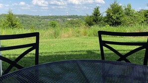 A table with two chairs facing a grassy field with trees and a distant view of a hill with a water tower. - ••Newly remodeled and family friendly! AMAZING Strip views & close to it ALL!! (Branson)