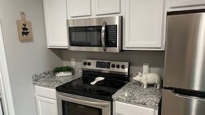 A kitchen with white cabinets, a stainless steel stove, a microwave, and a refrigerator. - ••Newly remodeled and family friendly! AMAZING Strip views & close to it ALL!! (Branson)