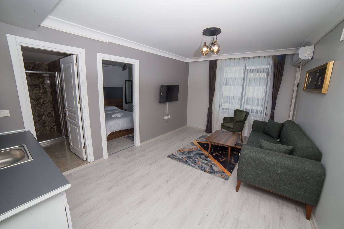 A modern living room with a grey sofa, a wooden coffee table, and a TV mounted on the wall.