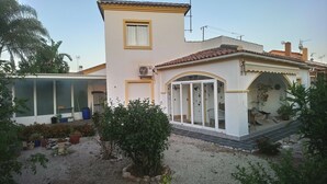 Ein zweistöckiges Haus mit Balkon, Garage und kleinem Garten mit verschiedenen Pflanzen.