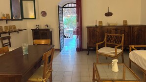 A dining area with a wooden table and chairs, a cabinet with decorative items, and a view through an open door to an outdoor area. - Farmhouse/ house hill (Parghelia)