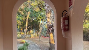 An archway leading to a garden with trees, a hammock, and a fire extinguisher on the wall. - Farmhouse/ house hill (Parghelia)