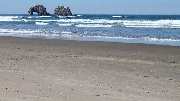 Uma praia com uma formação rochosa natural no oceano.