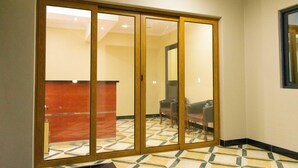 A hotel lobby with a check-in counter, a seating area with chairs, and a patterned floor.