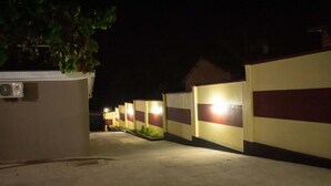 A nighttime view of a hotel corridor with uniform walls and a series of lights along the path.