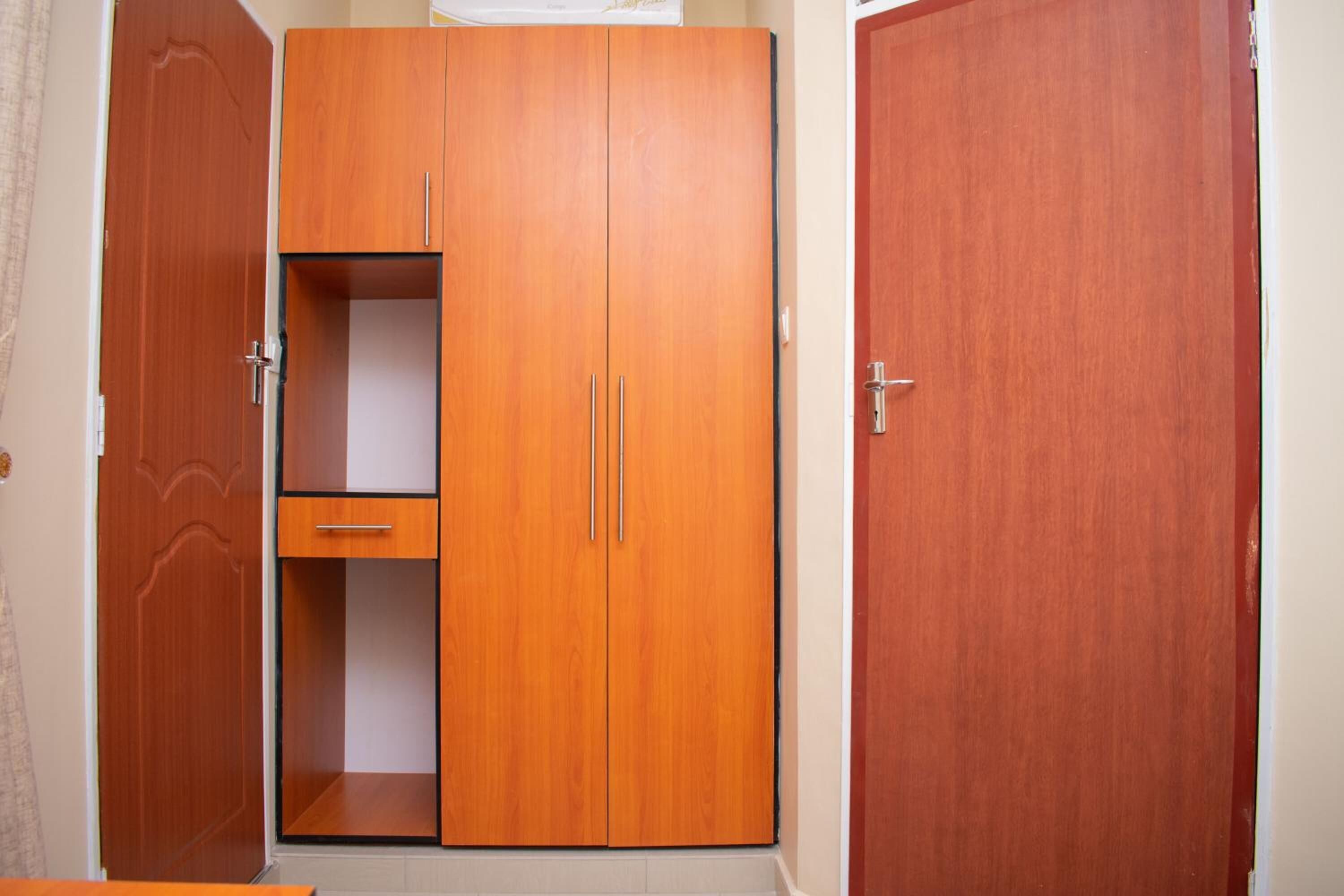 Una habitación con un armario de madera, un mueble pequeño y una puerta.