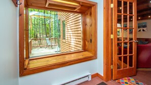 A room with a large window, a wooden door, and a view of an outdoor deck. - Trailside off West Side! (North Conway)