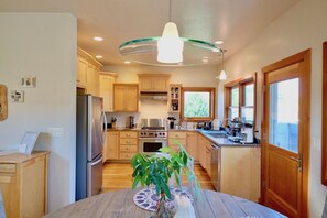 A modern kitchen with wooden cabinets, stainless steel appliances, and a central island with a vase of green plants.