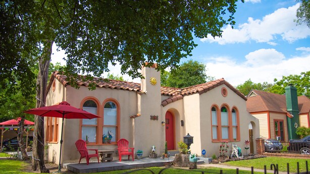 A house with a red door, a patio with red chairs, and a small garden.