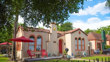 A house with a red door, a patio with red chairs, and a small garden.