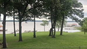 A grassy area with trees and a body of water. There is a dock and a pavilion in the background. - Sunrise Shores - Waterfront Cottage sleeps 8.   (Chandler)