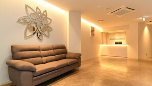 A modern hotel lobby with a sofa, a reception desk, and a decorative wall piece. - Hotel Wisteria Nara (Nara)