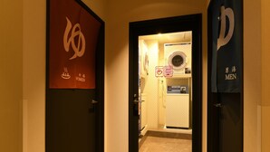 A hotel entrance with a glass door leading to a bathroom with a shower, toilet, and sink. - Hotel Wisteria Nara (Nara)