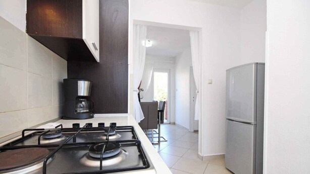A kitchen with a gas stove, coffee maker, and a refrigerator. - Holiday apartment with air conditioning near the beach (Baška)