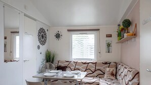 A compact living space with a dining area, a sofa, and a window with blinds. - 137. For an unforgettable holiday (Saint-Jean-de-Monts)