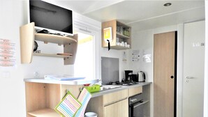 A modern kitchen with wooden cabinets, a built-in oven, a coffee maker, and a television mounted above the counter. - 137. For an unforgettable holiday (Saint-Jean-de-Monts)