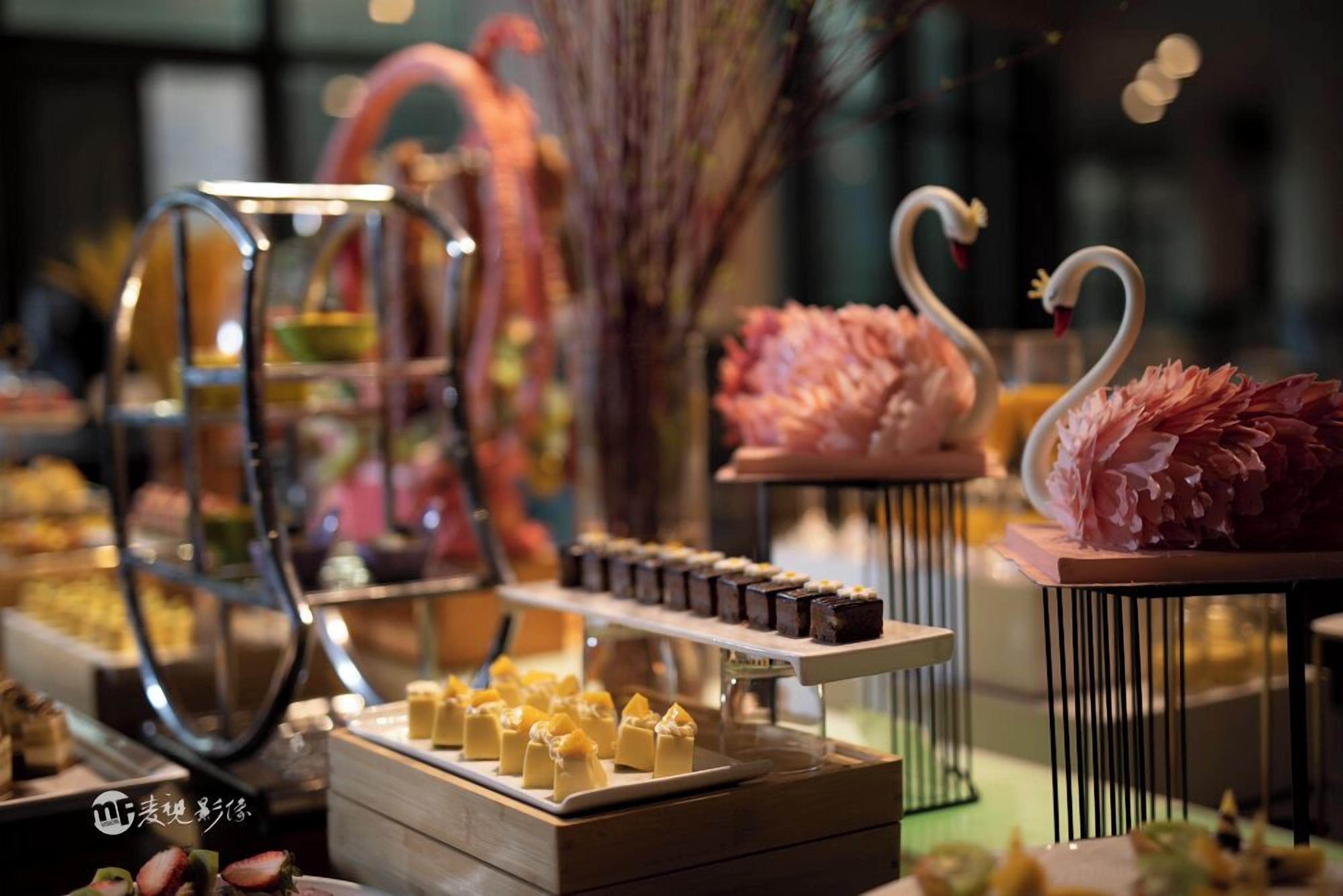 A dessert display with various sweets and a decorative flamingo centerpiece.