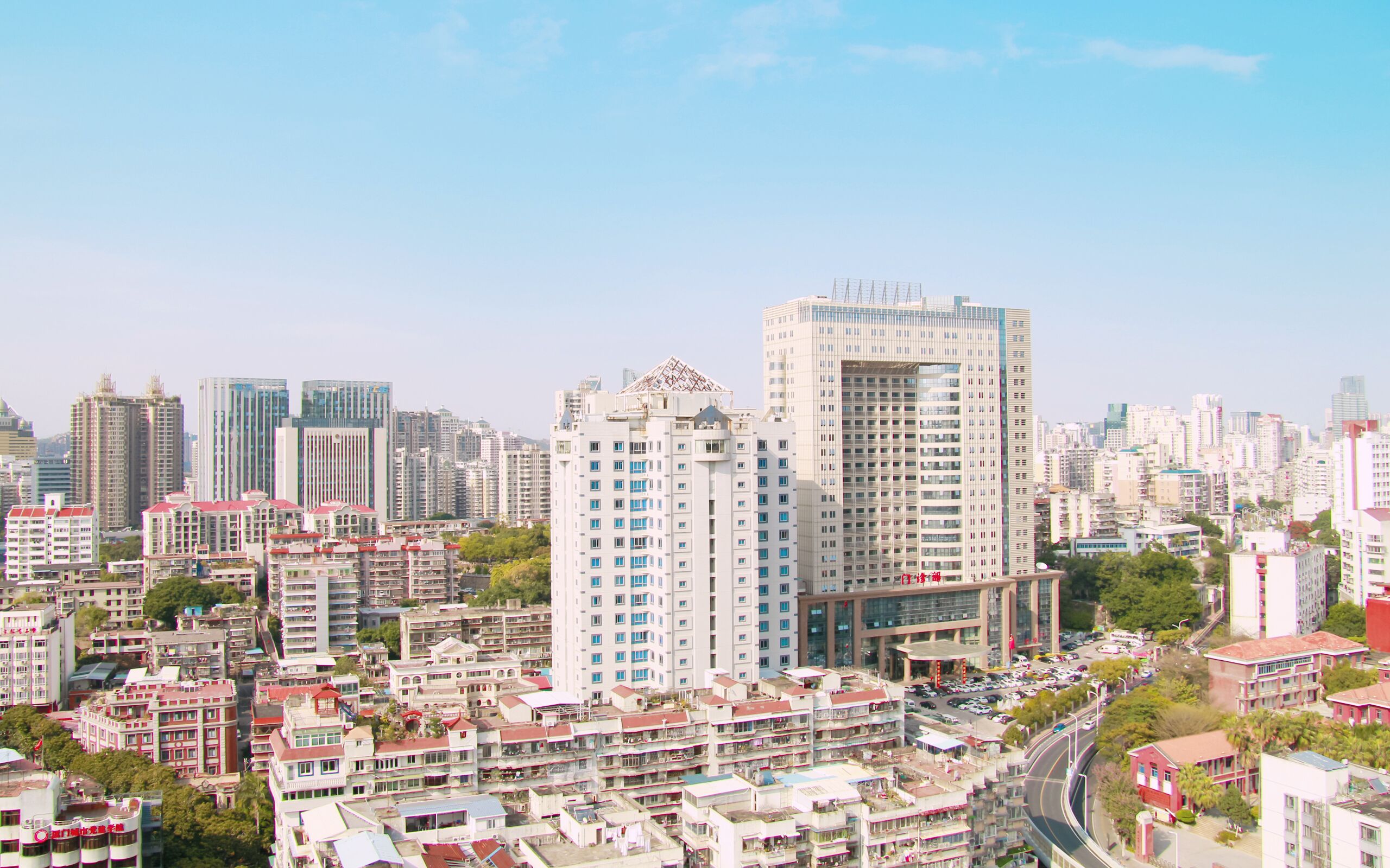 A high-rise building with a modern design, surrounded by other buildings and a busy street.