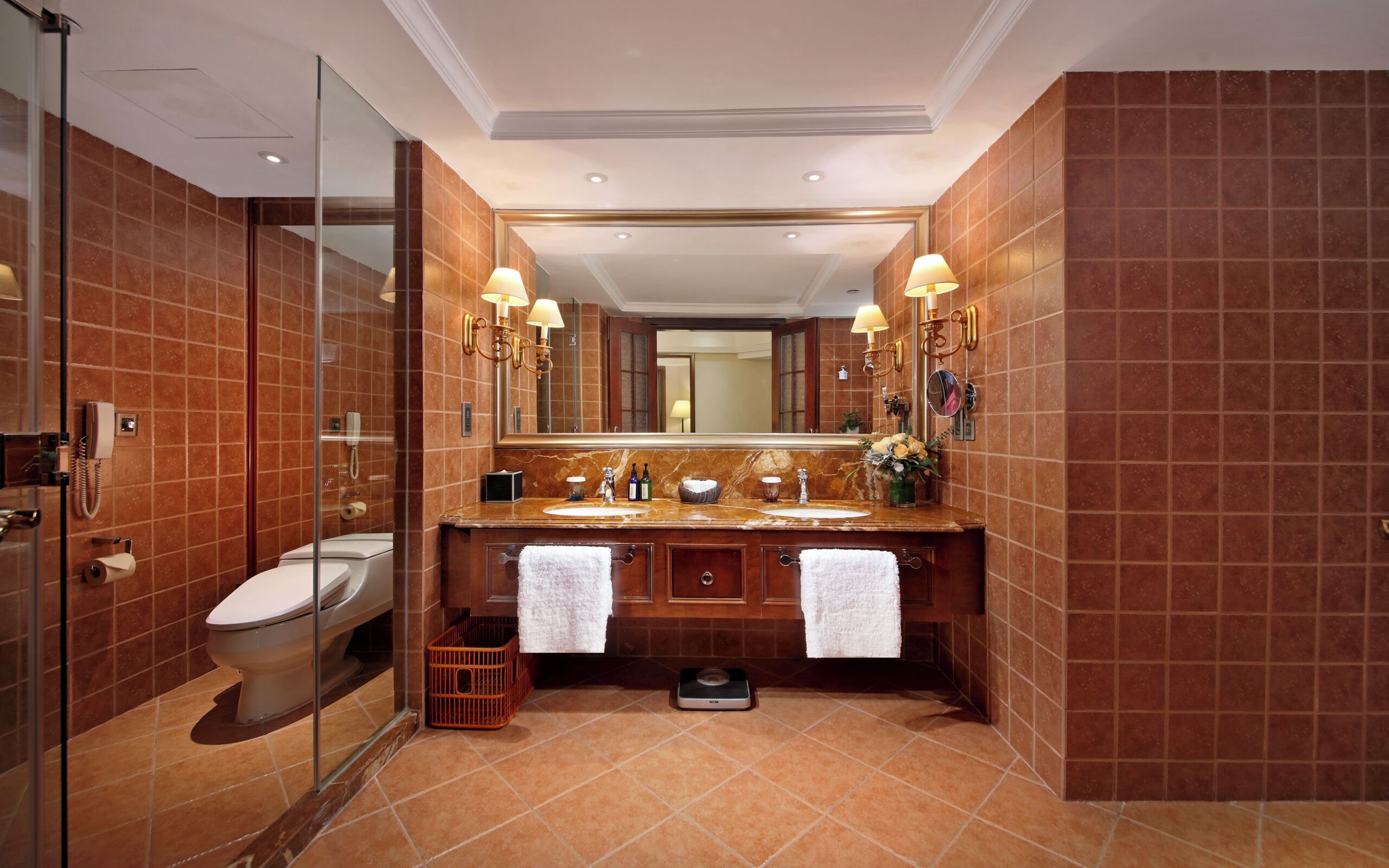 A modern bathroom with a glass shower enclosure, a double sink vanity with a marble countertop, and a large mirror above the sink.