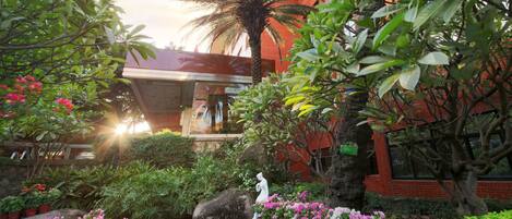 Un jardin avec un étang, des plantes en pot et une statue.