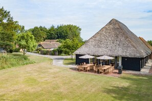 A thatched-roof building with outdoor seating and a pathway leading to it. - Great Higham Barn by Bloom Stays -  sleeps 26 guests  in 7 bedrooms (Sittingbourne)