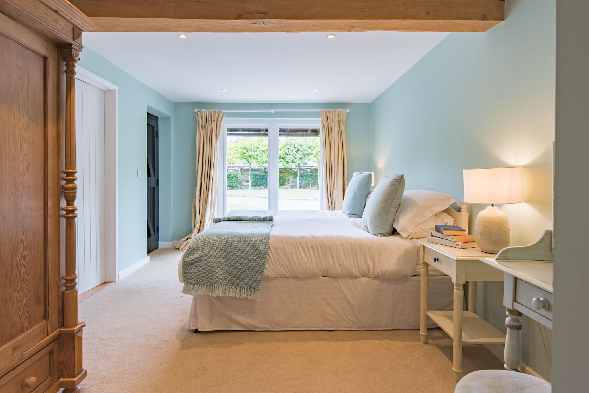 Une chambre avec un grand lit, un bureau et une fenêtre avec des rideaux.