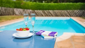 A poolside table with a bowl of strawberries, two glasses, and a book titled "The Murdos in Her Name" by Edgar Allen Poe. - Great Higham Barn by Bloom Stays -  sleeps 26 guests  in 7 bedrooms (Sittingbourne)