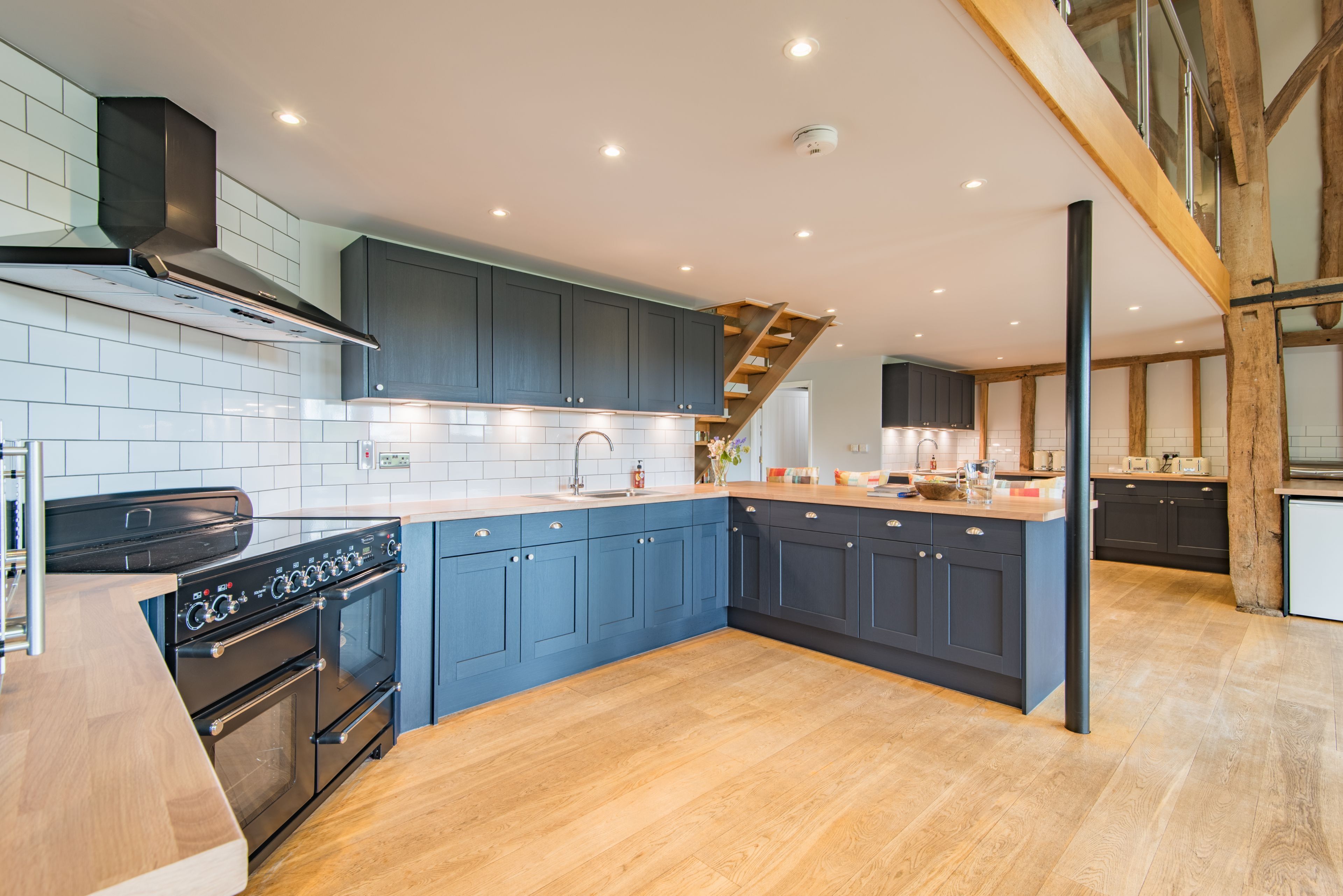 A modern kitchen with dark blue cabinets, a wooden countertop, and a built-in oven.