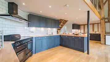 A modern kitchen with dark blue cabinets, a wooden countertop, and a built-in oven.