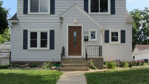 A two-story house with a front door, a mailbox, and a number '212' on the wall. - Single Level Living with Comfortable Recliners (Rochester)