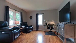 A living room with a flat-screen TV, two leather recliners, a desk with a chair, and a cabinet. - Single Level Living with Comfortable Recliners (Rochester)