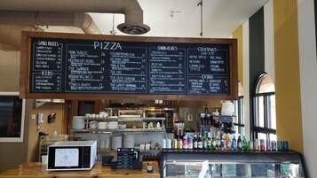 Un restaurant dont le menu, écrit à la craie sur un tableau noir, propose des pizzas, des sandwichs et des cocktails.