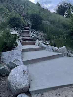 A concrete staircase with stone steps and large boulders on either side, leading up a grassy slope. - "Together On The Lake" at La Casa Resort (Kelowna)
