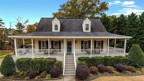 Une maison à deux étages avec un porche couvert, une porte d’entrée et une petite fenêtre au deuxième étage.