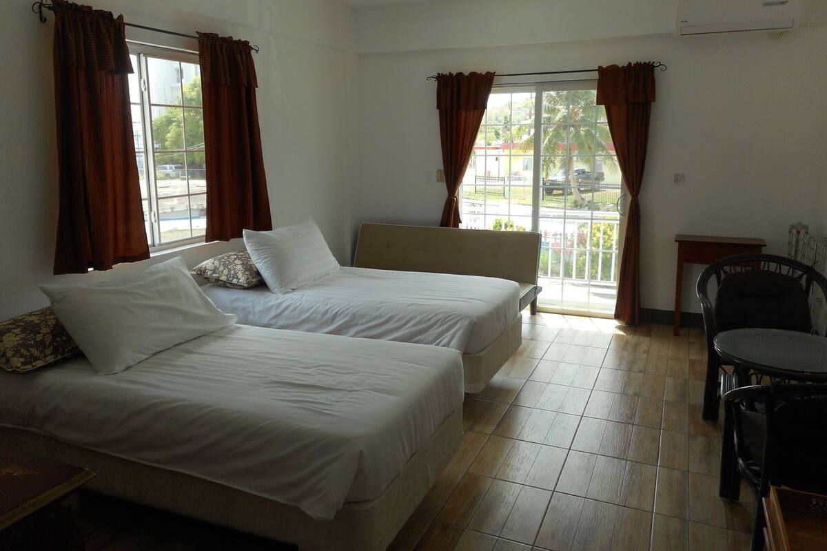 A room with two beds, a small table, and a chair.
