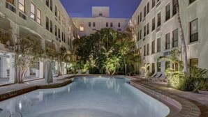 Una piscina rodeada de palmeras y un edificio con varios balcones.