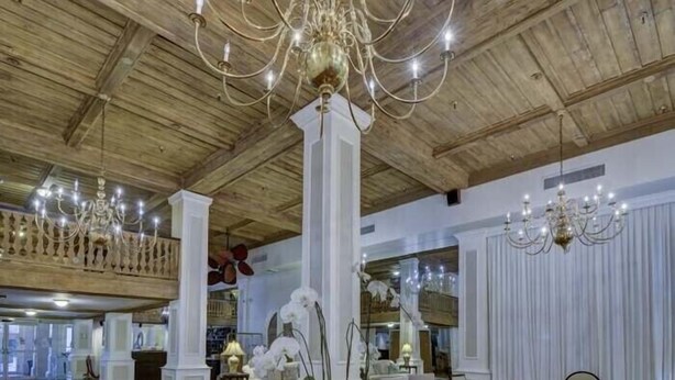 Un vestíbulo amplio con techos altos, vigas de madera y varios candelabros.