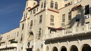 Un edificio histórico con múltiples arcos, un balcón con barandillas blancas y una torre con cúpula.