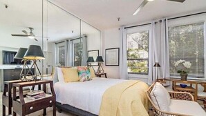 Un dormitorio con cama, mesitas de noche, una silla y ventilador de techo.