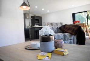 A modern living room with a dining table, a potted plant, and a patterned bowl. - Twin Camellias - Redwoods, Modern, Sleeps 6 (Rotorua)
