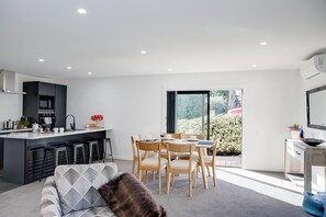 Eine moderne Küche mit Essbereich, einer Couch und Blick auf Grünfläche.