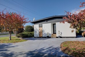A modern two-story house with a garage, a driveway, and a well-maintained lawn. - Twin Camellias - Redwoods, Modern, Sleeps 6 (Rotorua)