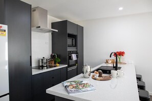 A modern kitchen with a built-in oven, microwave, and a coffee station.