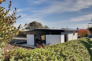 Ein modernes Haus mit flachem Dach, einer Terrasse mit Gartenmöbeln und einem gepflegten Garten.