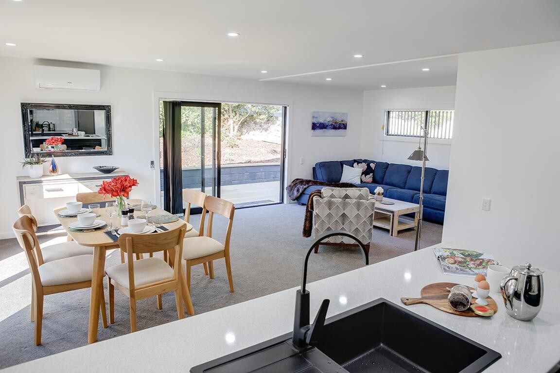 A modern living space with a dining area, a sofa, and a kitchen area.