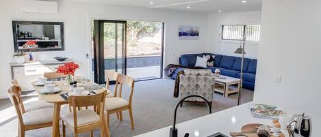 A modern living space with a dining area, a sofa, and a kitchen area.