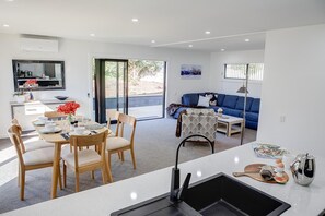 A modern living space with a dining area, a sofa, and a kitchen area.