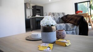 Ein modernes Wohnzimmer mit Couchtisch, einer Vase mit weißen Blumen, einer gemusterten Tasse und einer Zeitschrift.