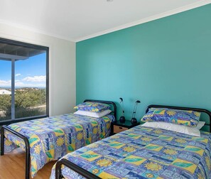 A bedroom with two beds, a large window, and a view of the outside.