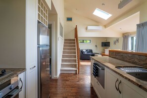 Una cocina con una escalera de madera que lleva a una sala de estar.